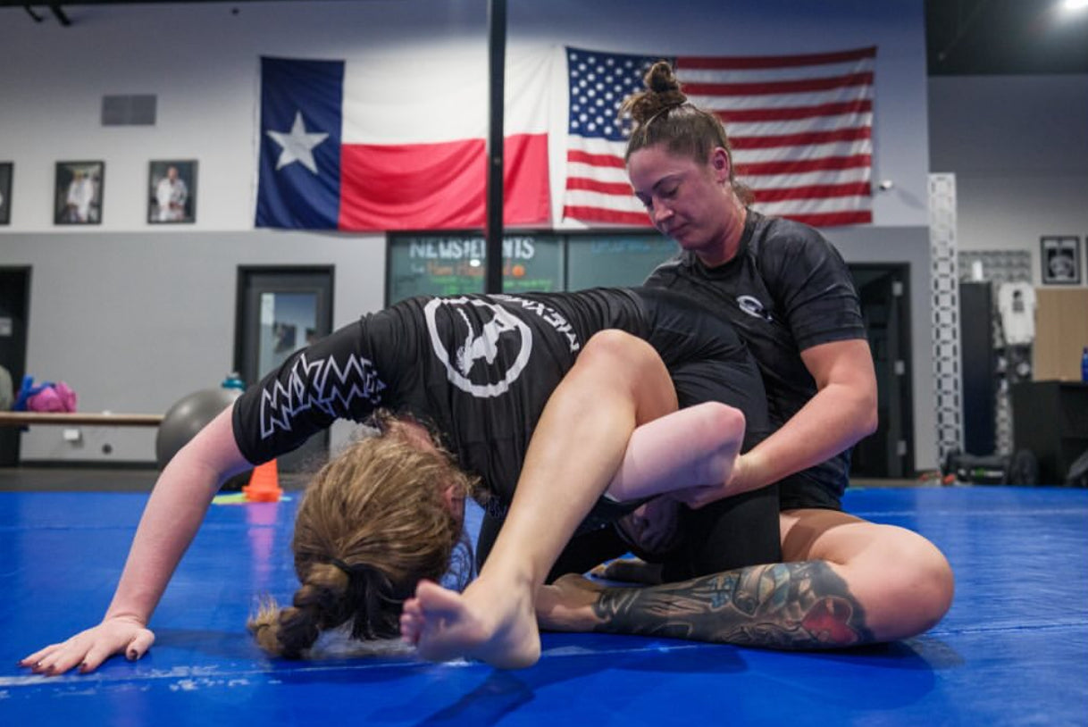 Two female jiu-jitsu practitioners find themselves in an awkward position, contemplating their escapes and defenses.